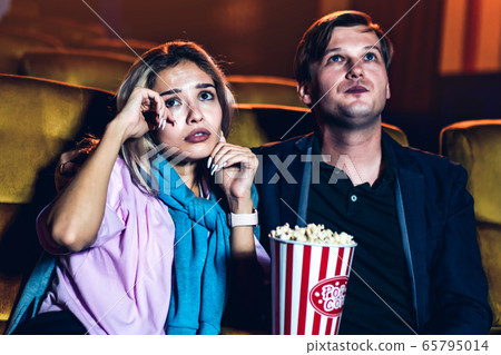 Caucasian man and woman watching a sad movie Caucasian man and woman watching a sad movie 65795014