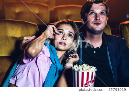 Caucasian man and woman watching a sad movie Caucasian man and woman watching a sad movie 65795019
