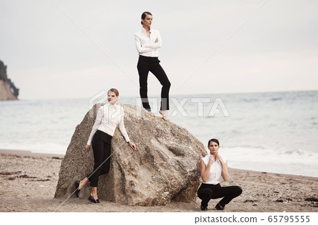 A young girl pulls her girlfriend's hand on a sandy beach, against the sea. A young girl pulls her girlfriend's hand on a sandy beach, against the sea. 65795555