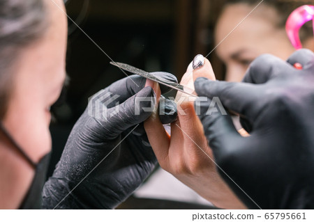Close-up of hardware milling cutter for removing gel polish. Apparatus manicure in beauty salon. Manicurist with electric nail drill remove old gel from client nails. Process of replacing old shellac. 65795661