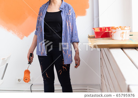 Close-up of middle-aged woman with painting roller indoors. Redecoration, renovation, apartment repair and refreshment concept. 65795976