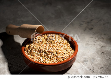 Raw green buckwheat in a brown clay bowl Raw green buckwheat in a brown clay bowl 65796266