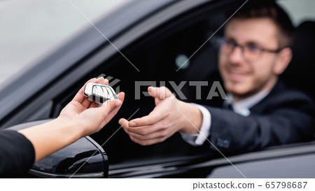 Young man taking auto key, sitting on driver's seat 65798687