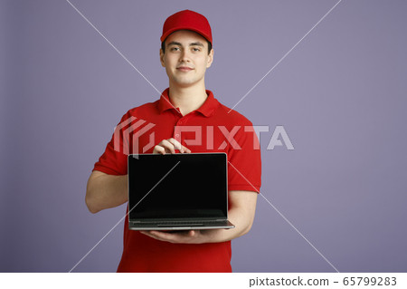 Order courier at home online. Deliveryman holding laptop with blank screen Order courier at home online. Deliveryman holding laptop with blank screen 65799283