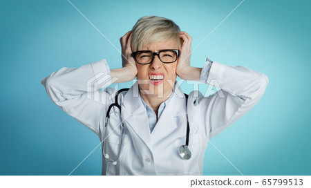 Headache from problems in medicine. Upset doctor holds her head with hands and closes eyes Headache from problems in medicine. Upset doctor holds her head with hands and closes eyes 65799513