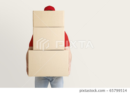 Online shopping and package delivery. Courier holds many large parcels, covering face Online shopping and package delivery. Courier holds many large parcels, covering face 65799514