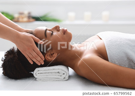 Young black woman getting head massage from massage therapist 65799562