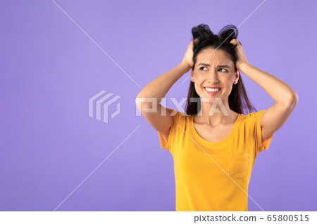 Confused puzzled young woman grabbing head at studio Confused puzzled young woman grabbing head at studio 65800515