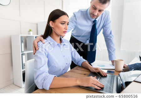 Lustful Boss Sexually Harassing Woman Coworker Sitting In Office Lustful Boss Sexually Harassing Woman Coworker Sitting In Office 65800516