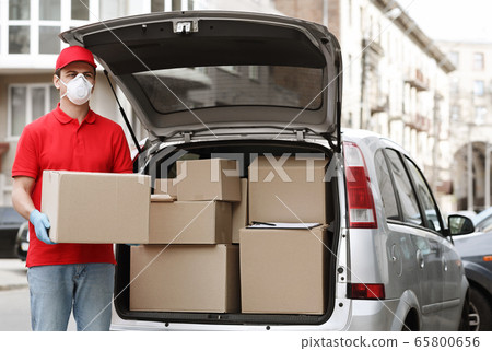 Many orders, a lot of deliveries concept. Courier holds big parcel near the car Many orders, a lot of deliveries concept. Courier holds big parcel near the car 65800656
