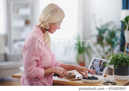 Senior woman preparing food in kitchen indoors, following food vlogger. Senior woman preparing food in kitchen indoors, following food vlogger. 65800965