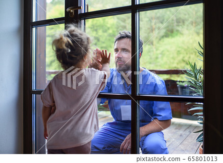Doctor coming to see family in isolation, window glass separating them. Doctor coming to see family in isolation, window glass separating them. 65801013