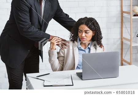 Workplace harassment. Disgusted female secretary stopping her boss from molesting her at company office Workplace harassment. Disgusted female secretary stopping her boss from molesting her at company office 65801018