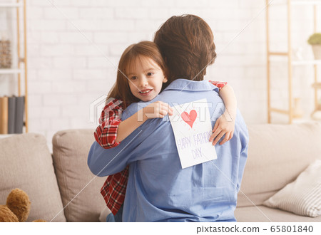 Cute little girl hugging dad, holding greeting card 65801840