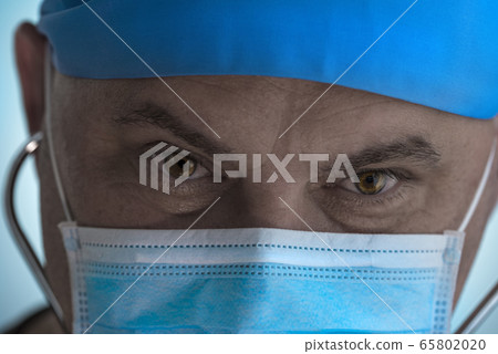 Portrait of tired doctor. Doctor wearing medical mask looking into camera Portrait of tired doctor. Doctor wearing medical mask looking into camera 65802020