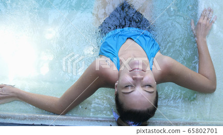 Top of view of beautiful young woman relaxes in a hydromassage jacuzzi, in swimming pool. Concept: spa procedures, body massages, spa cream, relax, spa water treatments Top of view of beautiful young woman relaxes in a hydromassage jacuzzi, in swimming pool. Concept: spa procedures, body massages, spa cream, relax, spa water treatments 65802701