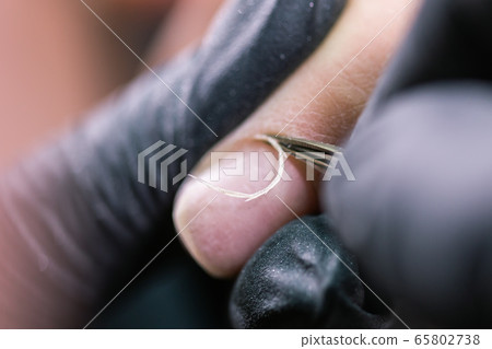 Hardware manicure in a beauty salon. Female manicurist is applying electric nail file drill to manicure on female fingers. Mechanical manicure close-up. Concept body care. Hardware manicure in a beauty salon. Female manicurist is applying electric nail file drill to manicure on female fingers. Mechanical manicure close-up. Concept body care. 65802738