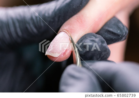 Manicurist use electric nail file drill in beauty salon. Perfect nails manicure process close up with burst flying debris. 65802739