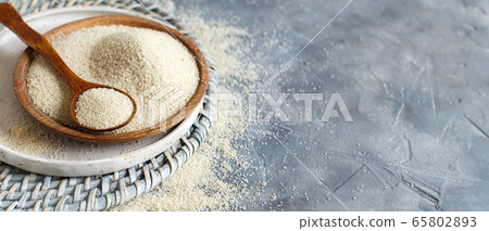 Raw uncooked fonio seeds with a spoon on a plate Raw uncooked fonio seeds with a spoon on a plate 65802893