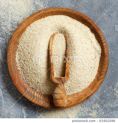 Raw uncooked fonio seeds with a spoon on a plate 65802896