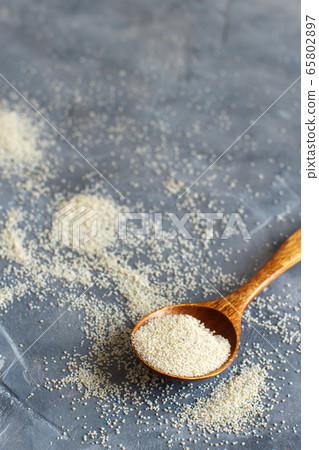 Raw uncooked fonio seeds with a spoon  on grey 65802897