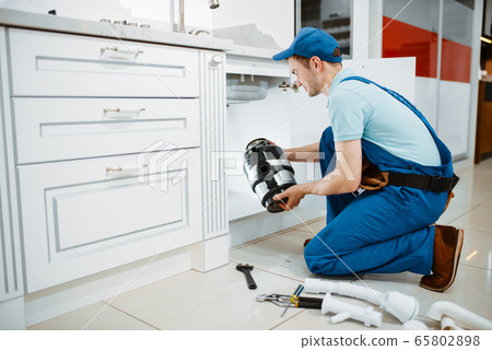 Male plumber in uniform installing disposer Male plumber in uniform installing disposer 65802898