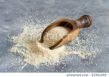 Raw uncooked fonio seeds with a spoon on grey 65802899