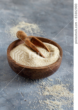 Raw uncooked fonio seeds in a bowl with a spoon on Raw uncooked fonio seeds in a bowl with a spoon on 65802900