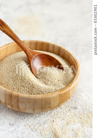 Raw uncooked fonio seeds in a bowl with a spoon on 65802901
