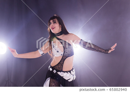 Young woman dancing in Tribal Fusion style. Belly dance on the stage. 65802940