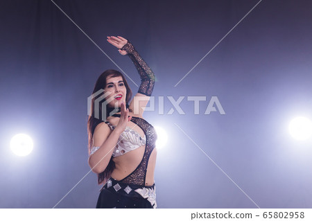 Young woman dancing in Tribal Fusion style. Belly dance on the stage. Copy space. 65802958