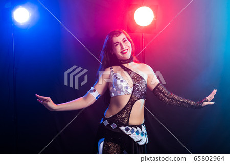 Young woman belly dancer in exotic dress with gold, dancing tribal fusion dance in studio. 65802964