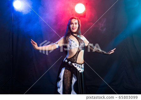 Belly dancer. Young attractive woman dancing tribal fusion on the stage. Oriental exotic dance. Belly dancer. Young attractive woman dancing tribal fusion on the stage. Oriental exotic dance. 65803099