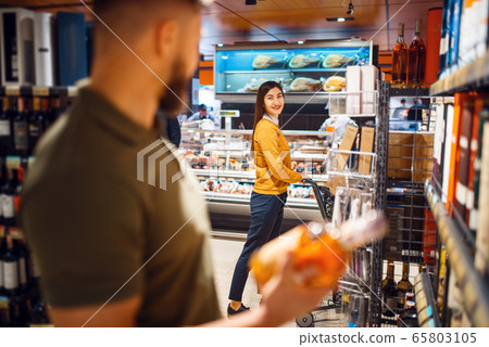 Family couple in grocery store, alcohol department Family couple in grocery store, alcohol department 65803105