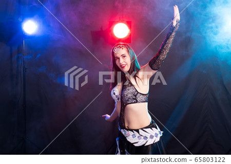 Young woman belly dancer in exotic dress with gold, dancing tribal fusion dance in studio. Young woman belly dancer in exotic dress with gold, dancing tribal fusion dance in studio. 65803122