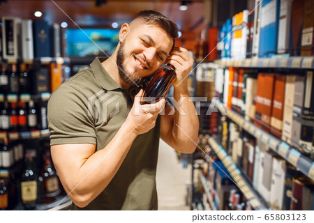 Man hugs bottle of alcohol in grocery store 65803123