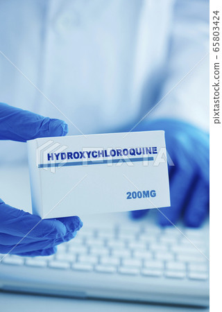 man in white coat with a box of hydroxychloroquine 65803424