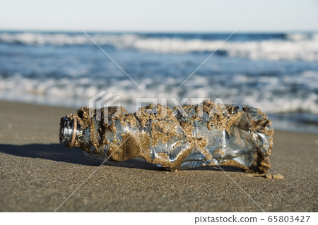 used plastic bottle on the sand of a beach used plastic bottle on the sand of a beach 65803427
