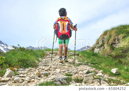 Little boy walks on mountain trail during an 65804252