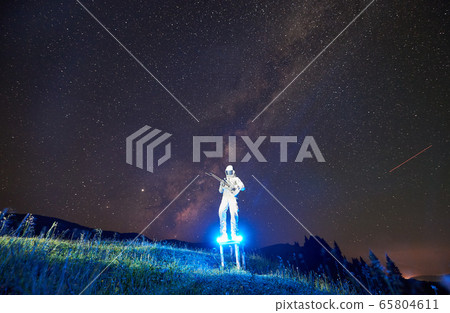 Astronaut playing guitar under beautiful night sky. 65804611
