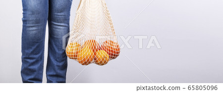 Young woman in blue jeans is on holds string bag Young woman in blue jeans is on holds string bag 65805096
