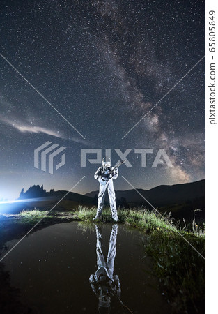 Space traveler playing guitar under beautiful night sky. 65805849