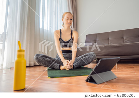 Fitness woman exercising on the floor at home and watching fitness videos in a tablet. People do Fitness woman exercising on the floor at home and watching fitness videos in a tablet. People do 65806203
