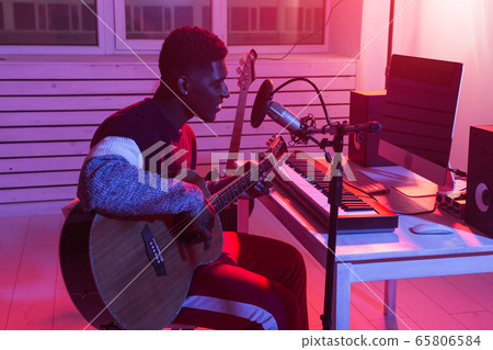 African american professional musician recording guitar in digital studio at home, music production technology concept. African american professional musician recording guitar in digital studio at home, music production technology concept. 65806584