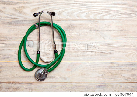 Top view of green stethoscope on yellow wooden Top view of green stethoscope on yellow wooden 65807044