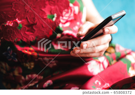 Young beautiful woman writes an SMS to her mobile phone 65808372