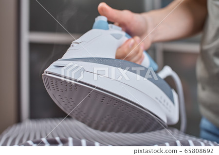 Steam boost on the modern iron. Woman ironing 65808692
