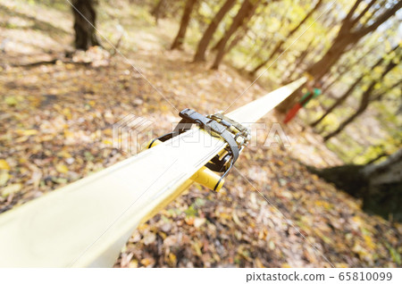 Equipment for slackline Slackline sling next to the machine and protection for the tree. stretched yellow-colored slackline in the autumn forest Equipment for slackline Slackline sling next to the machine and protection for the tree. stretched yellow-colored slackline in the autumn forest 65810099