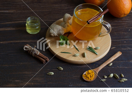 Ginger tea with saffron in a glass Cup and ingredients on a dark wooden table Ginger tea with saffron in a glass Cup and ingredients on a dark wooden table 65810552