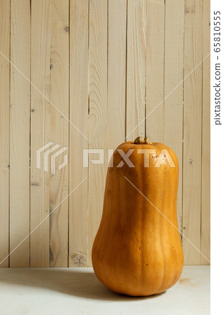 one large orange bottle-shaped pumpkin on a background of light boards, vertical frame with space one large orange bottle-shaped pumpkin on a background of light boards, vertical frame with space 65810555